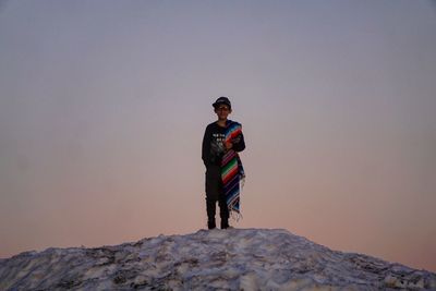 Boy standing on snow against clear sky