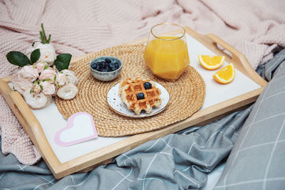 Romantic breakfast with waffles, orange juice and rose flowers and gift box