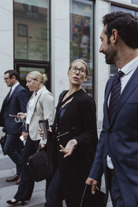 Entrepreneur talking to male while walking by coworkers in city