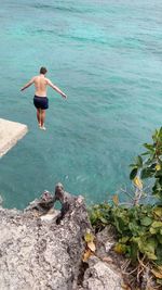High angle view of shirtless man jumping into sea