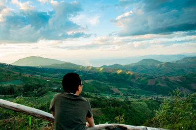 Rear view of man looking at mountains against sky