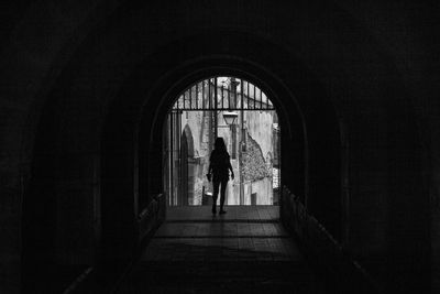 Rear view of silhouette woman walking in archway 