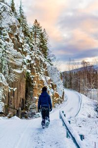 Rear view of boy walking on snow covered landscape