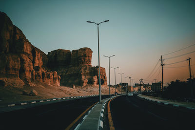Street in city against sky during sunset