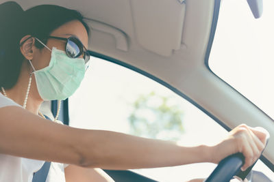 Traveler woman wearing medical mask and sunglasses driving a car 