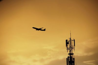 Low angle view of silhouette airplane against sky during sunset