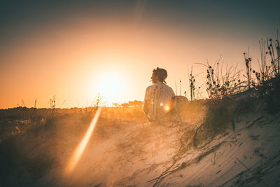 Man on field against clear sky during sunset