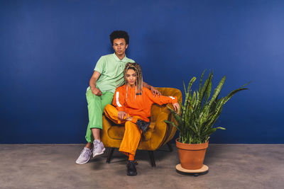 Young friends sitting on armchair at studio