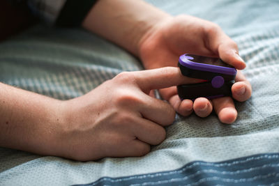 Close up of a person putting a pulse oximeter on their finger.