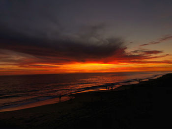 Scenic view of sea against dramatic sky during sunset