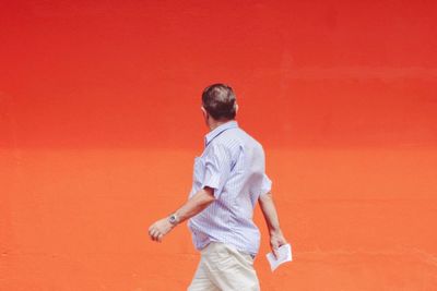 Full length of man playing against red wall