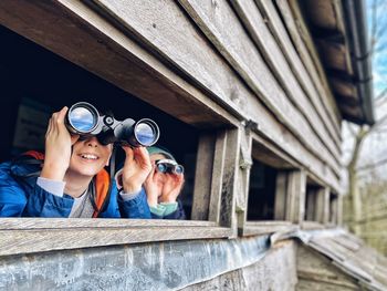 Portrait of children using binoculars in a bird hide.