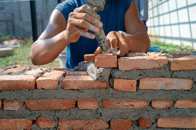 Midsection of worker building brick wall