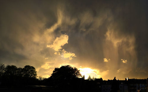 Silhouette of trees against cloudy sky