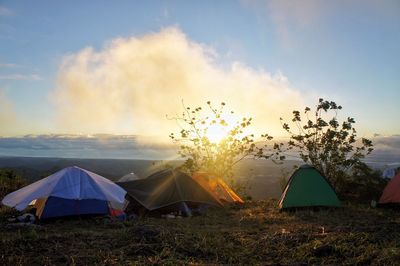 Tent on grass against sky at sunset