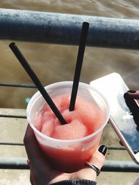 Cropped hand holding drink on sunny day