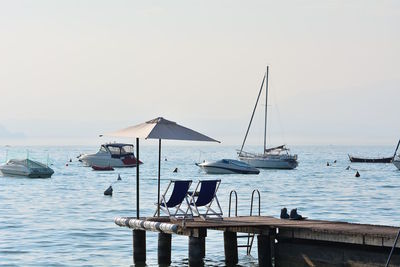 Sailboats moored in sea against clear sky