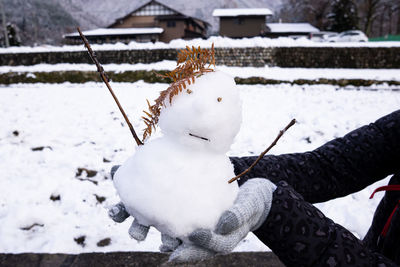 Close-up of snow on hand against snowcapped during winter