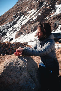 Side view of man sitting on rock