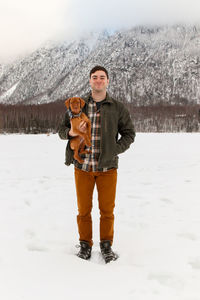 Portrait of young man standing on snow covered field