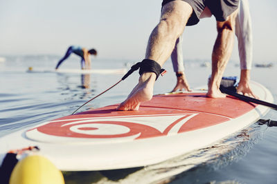 A standup paddle boarder balances in a yoga pose at sunrise in the fog