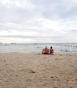 People sitting on beach against sky