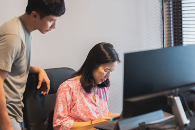 Freelance couple working from home at desk with desktop computer on table.