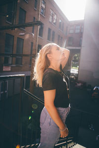 Side view of young woman standing on street in city