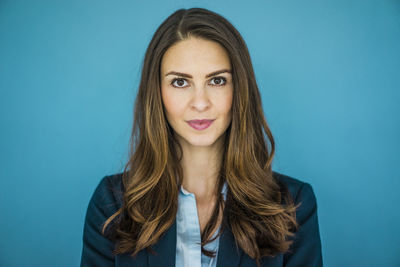 Portrait of businesswoman against blue background