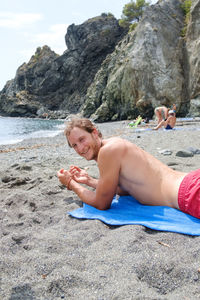 Full length of shirtless boy on rock at beach