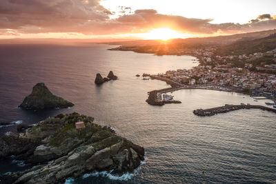 Aerial view of town by sea against sky during sunset
