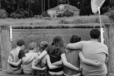 Rear view of friends standing by water