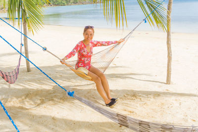 Full length portrait of smiling young woman on beach