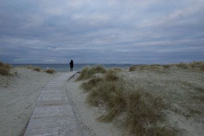 Rear view of woman on beach against sky