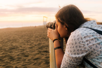 Woman photographing at beach during sunset