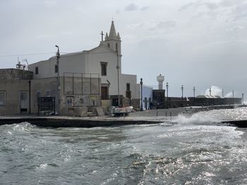 Buildings by sea against sky in city