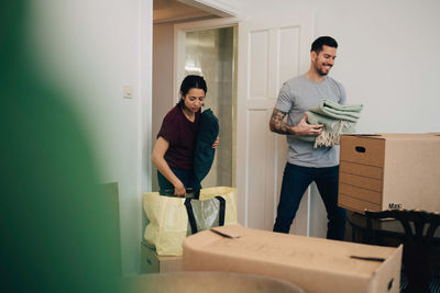 Couple unpacking boxes while standing in living room