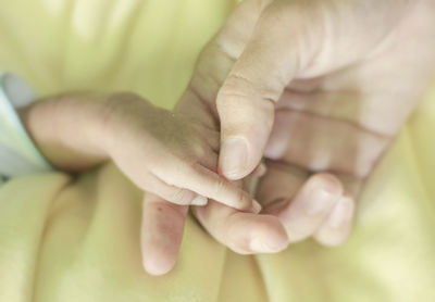 Close-up of father holding baby hand