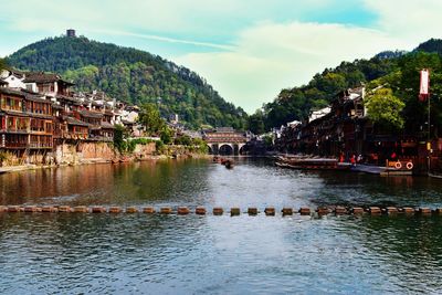 Scenic view of river by buildings against sky