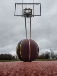 Surface level view of ball on basketball court against cloudy sky