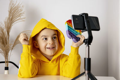 Adorable, cute, little boy blogger recording lifestyle blog, talking to camera of smartphone 