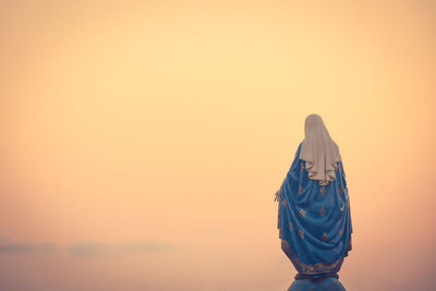 Rear view of statue against orange sky