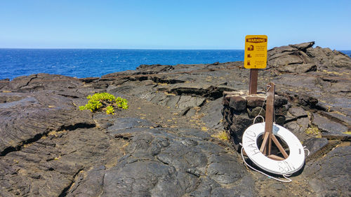 Close-up of information sign on beach against clear sky