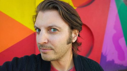 Close-up portrait of mid adult man standing against colorful plastic