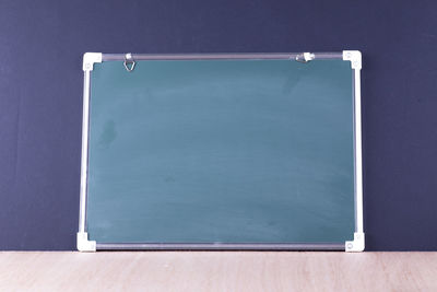 Close-up of blank blackboard on table against wall