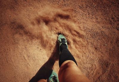 Low section of woman standing on sand