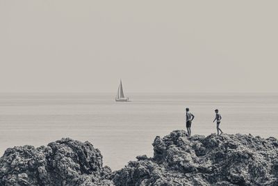 Sailboat on rock by sea against clear sky