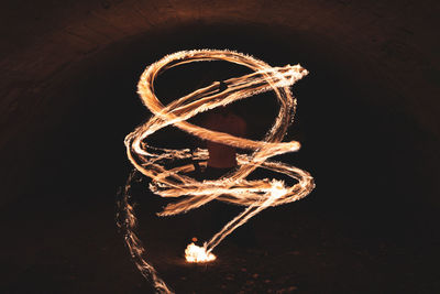 Male fire juggler performing skill in dark tunnel
