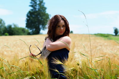 Young woman standing on field against sky