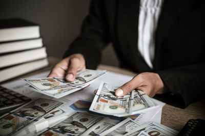 Midsection of businessman holding paper currency on table